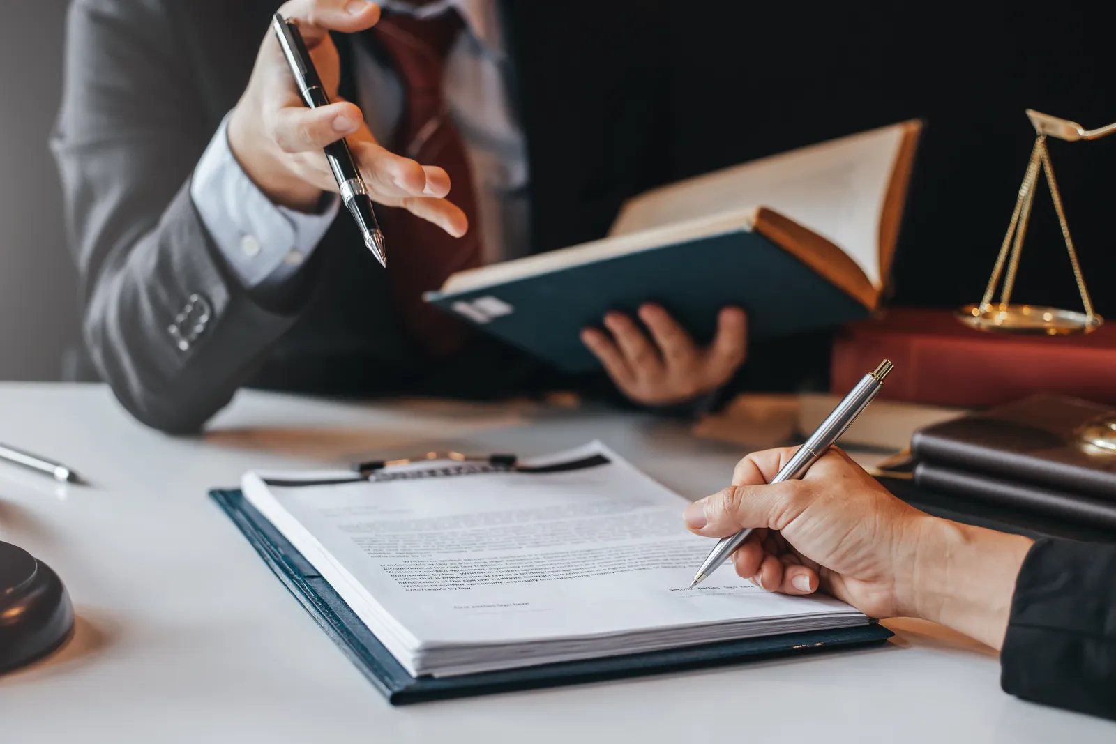 Profissionais analisando e assinando um contrato com orientação jurídica